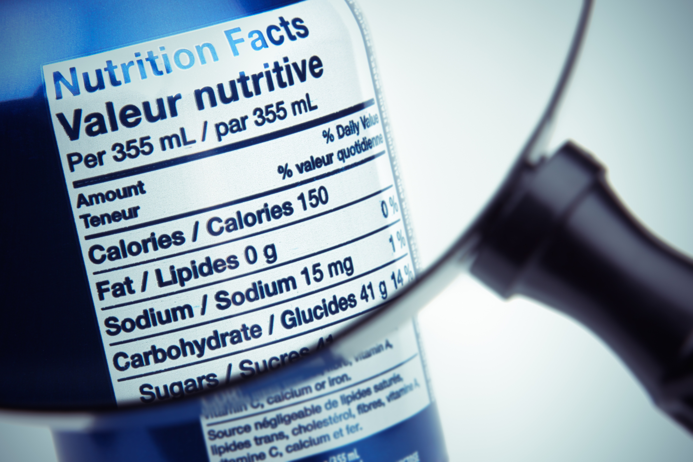 A magnifying glass gives a close up look at the nutritional facts of can of pop.